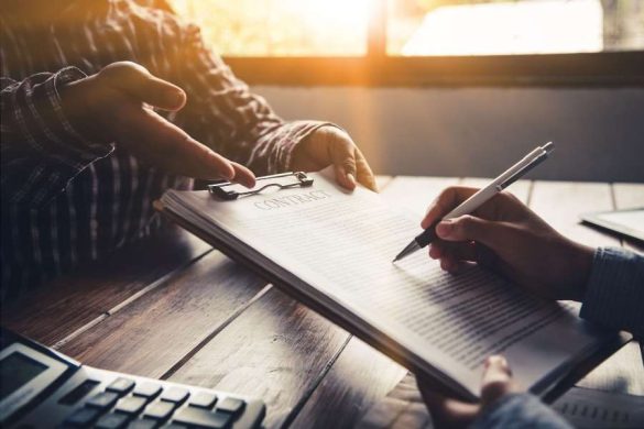 Deux personnes signant un contrat de location sur un bureau en bois dans le cadre d'une transaction en immobilier locatif