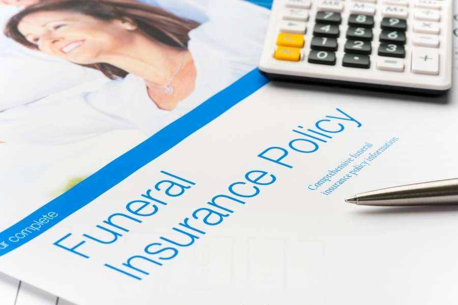 Un formulaire officiel de contrat d'assurance obsèques posé à côté d'une calculatrice.
